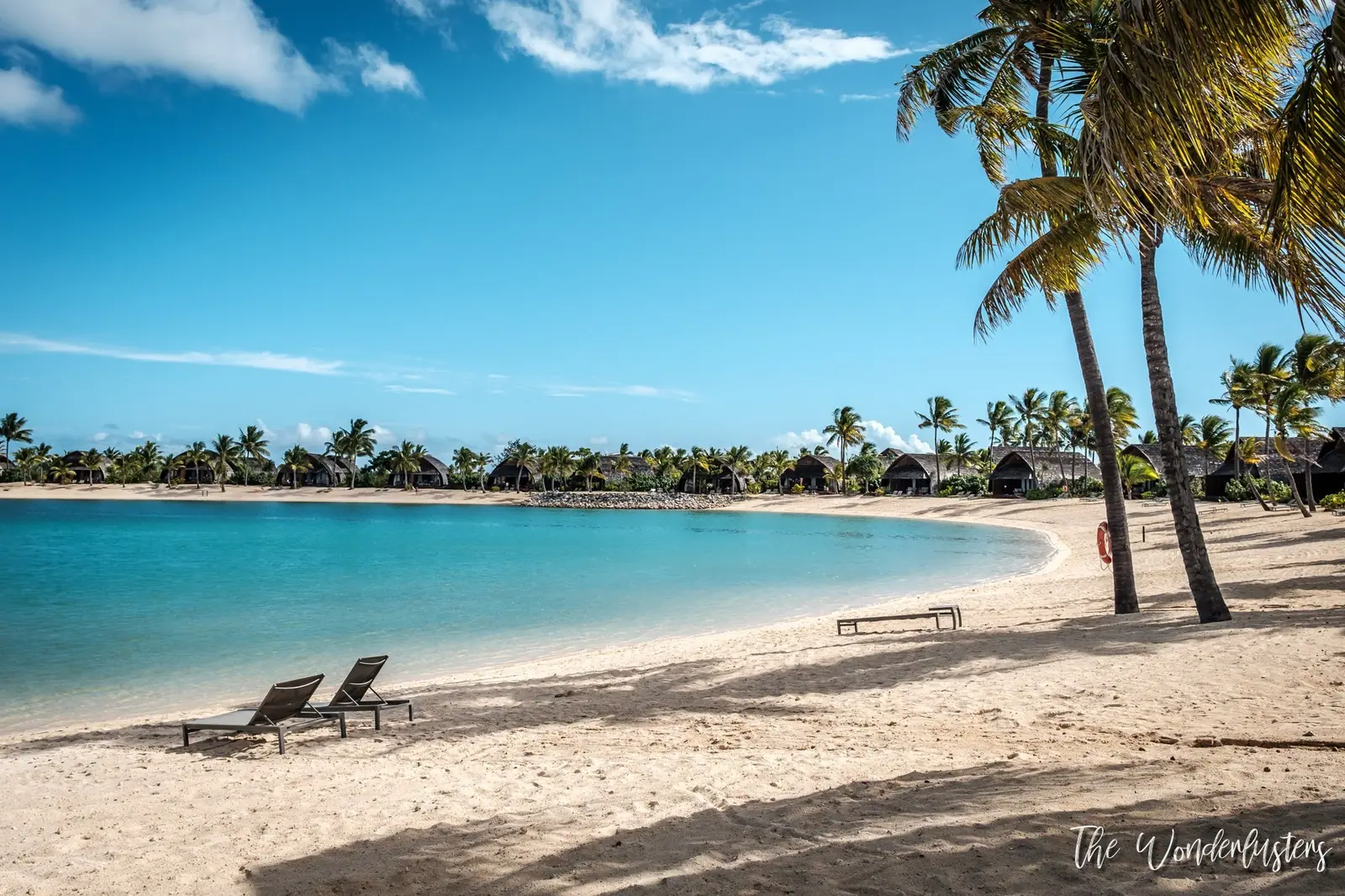 Palm-lined beach with loungers at the Fiji Marriott Resort Momi Bay
